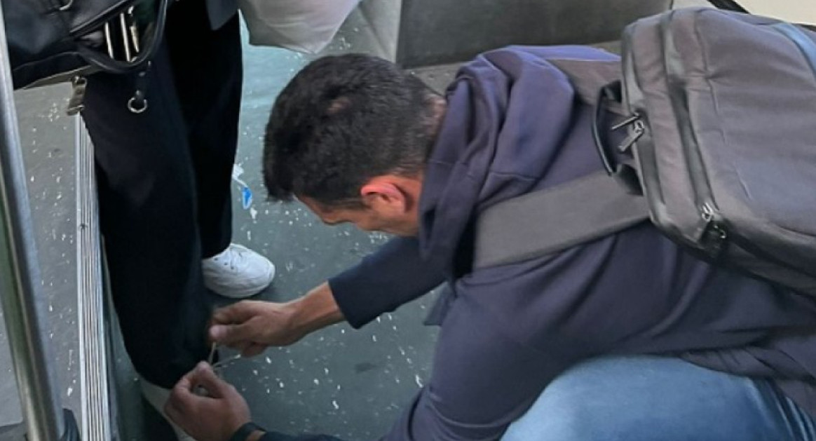 Lionel Scaloni atándole los cordones a una mujer en un colectivo. Foto: NA.