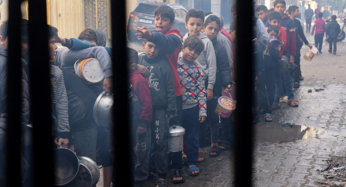 Niños palestinos esperan recibir comida cocinada en una cocina benéfica, en Rafah, Gaza. Reuters