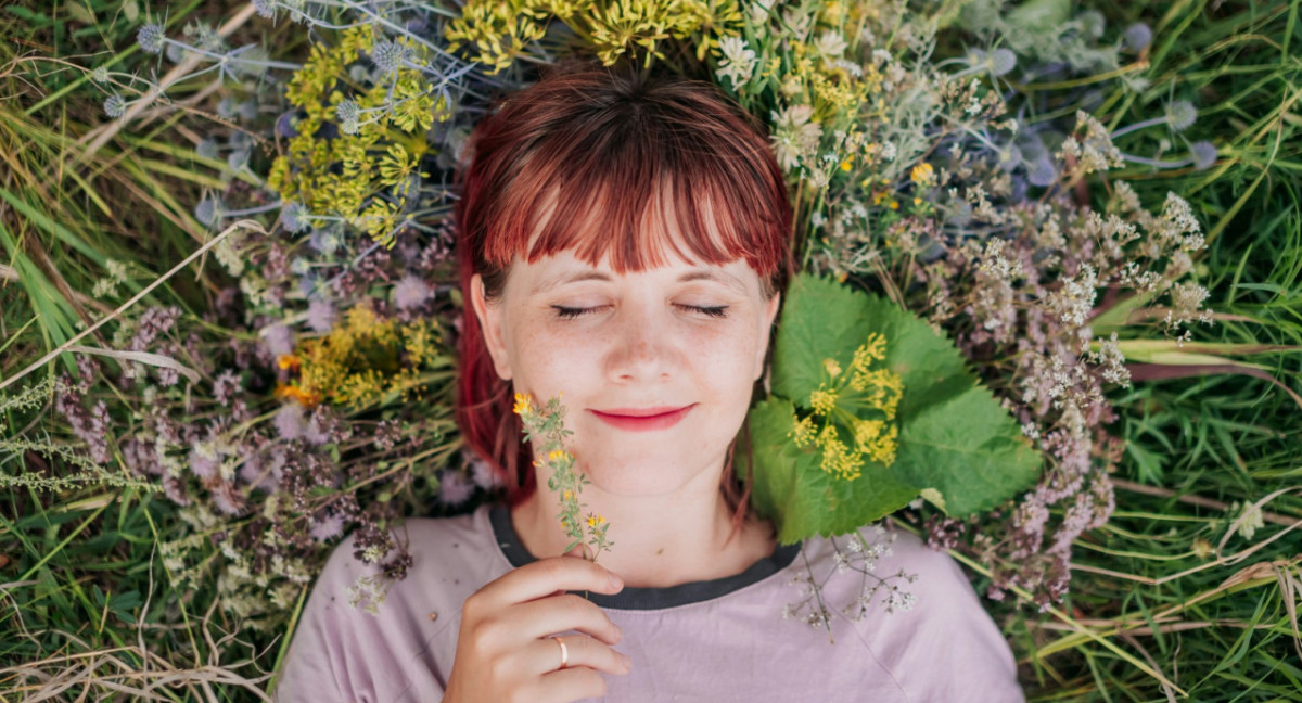 Felicidad. Una niña sonríe acostada en el pasto. Fto: Unsplash