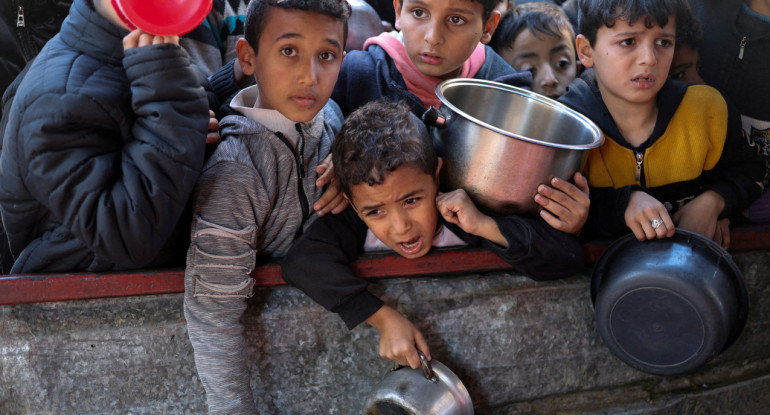 El hambre como "arma de guerra". Niños esperando comida en Gaza. Reuters