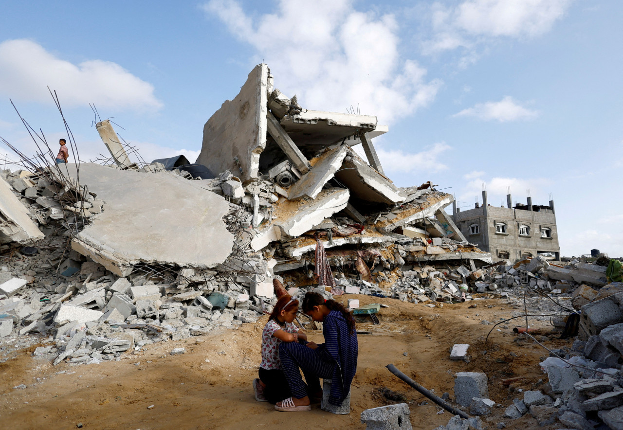 Niños palestinos sentados junto al lugar de un ataque israelí contra una casa. Foto: Reuters