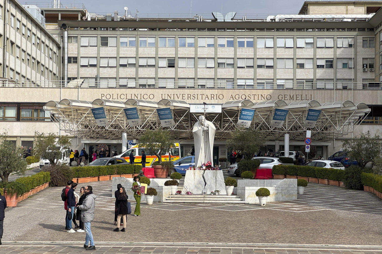 Velas y flores a los pies de la escultura de Juan Pablo II a las puertas del Hospital Gemelli de Roma donde permanece ingresado el papa Francisco. EFE