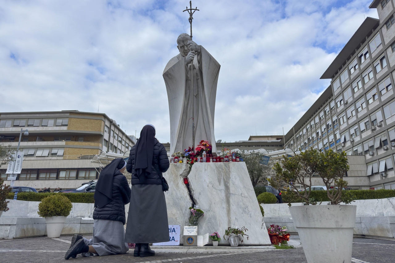 Velas y flores a los pies de la escultura de Juan Pablo II a las puertas del Hospital Gemelli de Roma donde permanece ingresado el papa Francisco. EFE